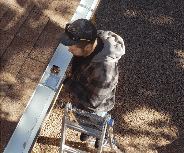 Best Buy Gutter Team member installing heat tape into a gutter system